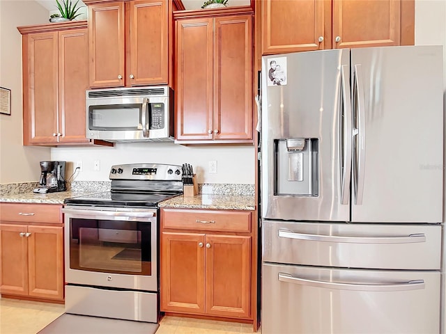 kitchen featuring appliances with stainless steel finishes, light stone counters, and light tile patterned flooring