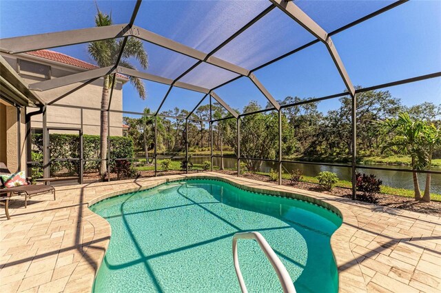 outdoor pool featuring a water view, a patio area, and glass enclosure