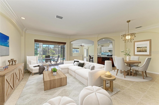 living area with ornamental molding, arched walkways, visible vents, and a notable chandelier