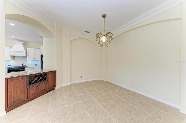 empty room with arched walkways, a chandelier, visible vents, baseboards, and ornamental molding