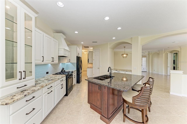 kitchen with arched walkways, a kitchen breakfast bar, a sink, and black appliances