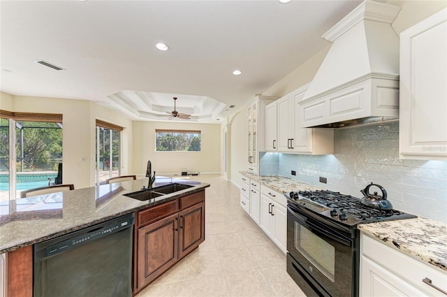 kitchen with a sink, visible vents, custom exhaust hood, black appliances, and a raised ceiling