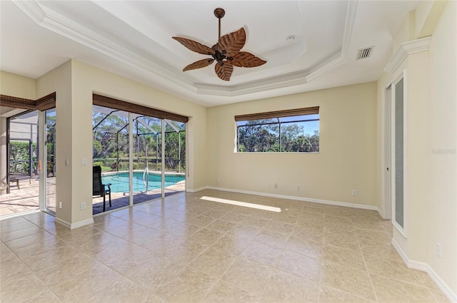 empty room with a raised ceiling, visible vents, baseboards, and a healthy amount of sunlight