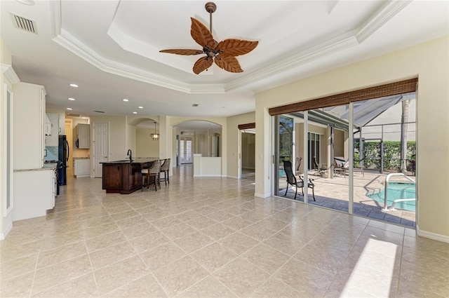 living area featuring arched walkways, a raised ceiling, crown molding, and baseboards