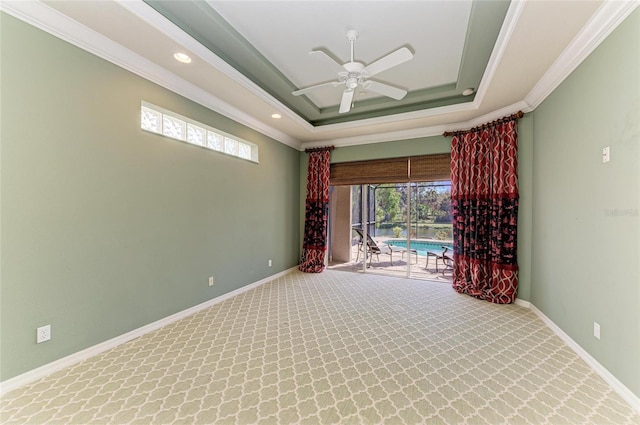 spare room with ornamental molding, a tray ceiling, baseboards, and carpet