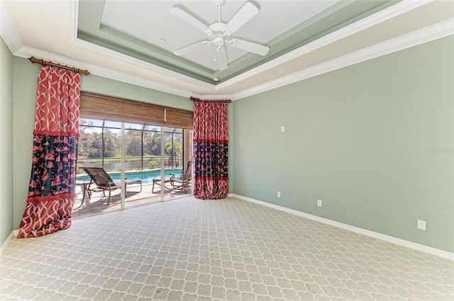 carpeted spare room featuring baseboards, a tray ceiling, a sunroom, and crown molding