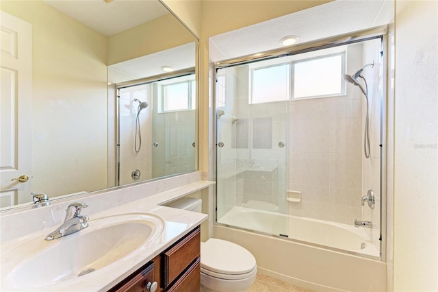 full bath with toilet, bath / shower combo with glass door, and vanity