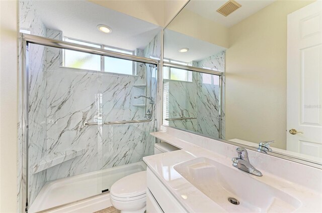 bathroom with a marble finish shower, recessed lighting, visible vents, toilet, and vanity