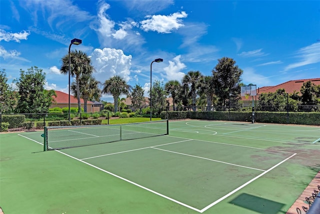 view of tennis court featuring community basketball court and fence