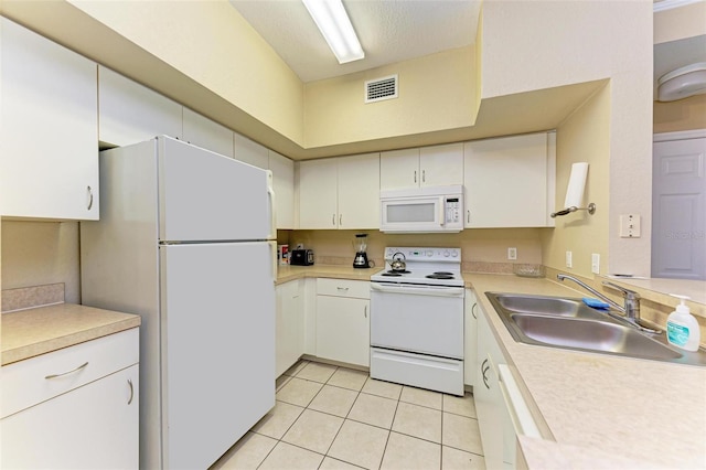 kitchen featuring white cabinetry, sink, light tile patterned flooring, and white appliances