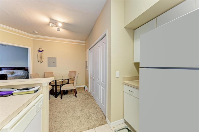 kitchen featuring white appliances, light carpet, white cabinets, crown molding, and a textured ceiling