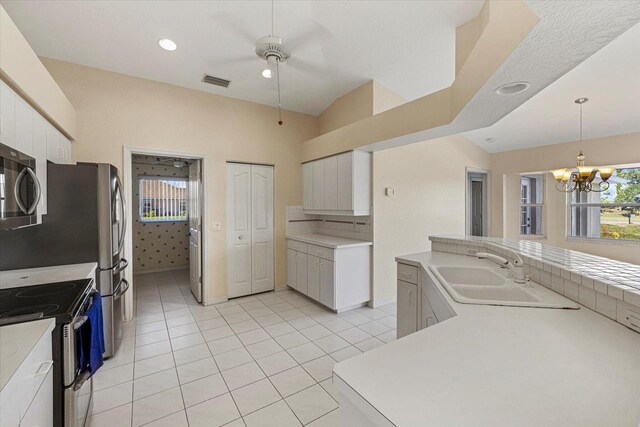 kitchen featuring appliances with stainless steel finishes, sink, white cabinetry, hanging light fixtures, and light tile patterned flooring