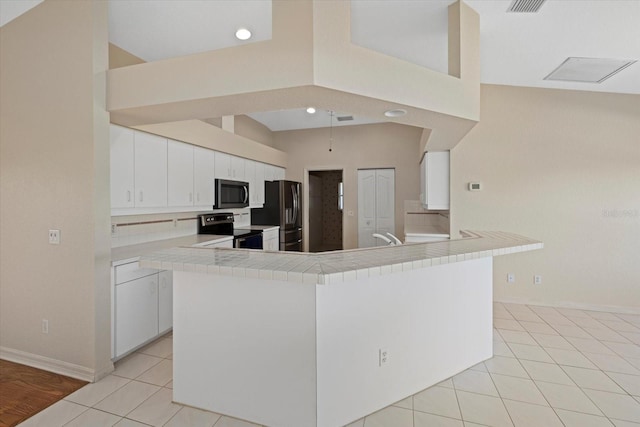 52 Fairway Rd, Rotonda West, FL 33947 - kitchen featuring stainless steel appliances, white cabinetry, light tile patterned floors, a peninsula, and tile counters