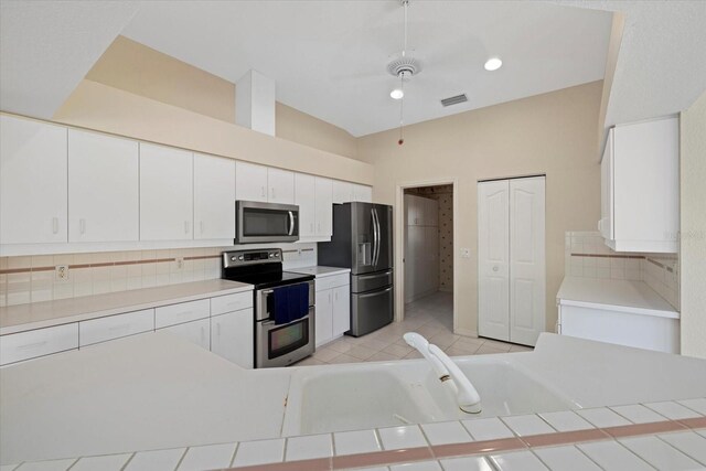 kitchen with decorative backsplash, stainless steel appliances, and white cabinetry