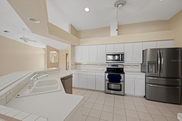 kitchen with stainless steel appliances, ceiling fan, sink, light tile patterned floors, and white cabinetry