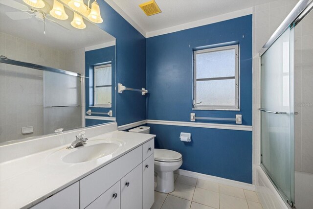 full bathroom featuring combined bath / shower with glass door, tile patterned floors, vanity, ceiling fan, and toilet