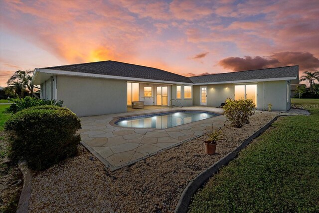 back house at dusk featuring a patio