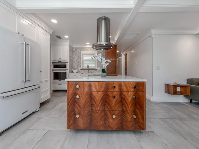 kitchen with island exhaust hood, tasteful backsplash, high end white fridge, a kitchen island, and white cabinetry