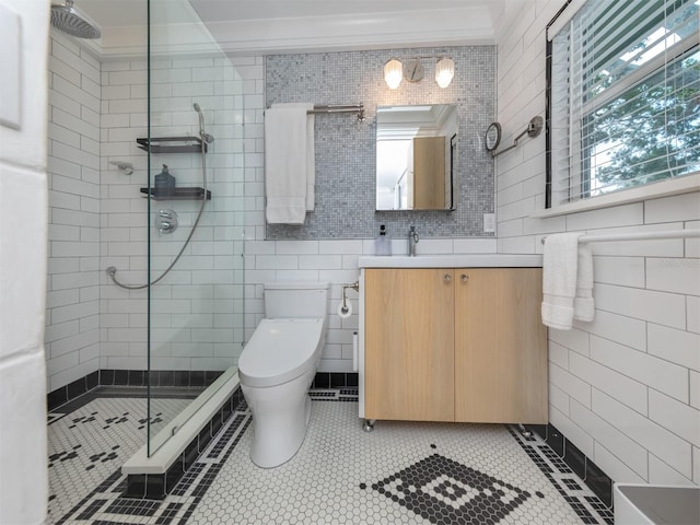 bathroom featuring vanity, tile patterned floors, toilet, ornamental molding, and a tile shower