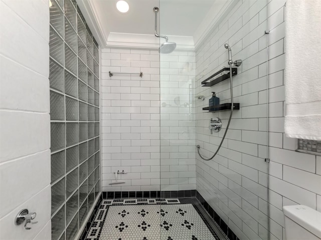 bathroom featuring a tile shower, toilet, tile patterned flooring, and ornamental molding