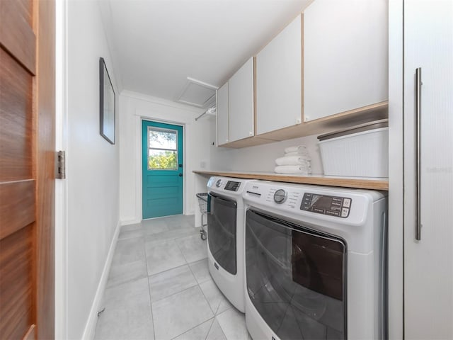 laundry area with washing machine and clothes dryer, light tile patterned floors, and cabinets