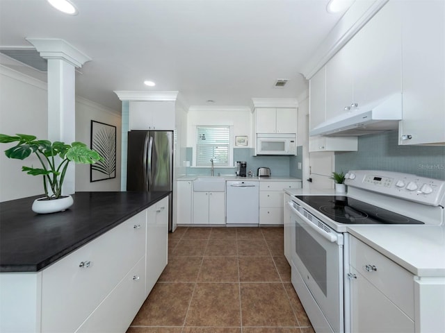 kitchen with ornamental molding, white appliances, dark tile patterned floors, sink, and white cabinets