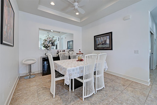 tiled dining area featuring a tray ceiling and ceiling fan