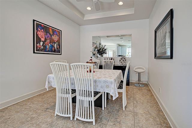 dining room featuring a raised ceiling, ceiling fan, and tile patterned flooring