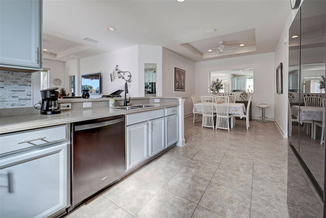 kitchen featuring a raised ceiling, ceiling fan, sink, and stainless steel dishwasher