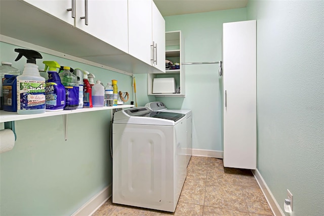 clothes washing area with cabinets, light tile patterned floors, and washing machine and clothes dryer