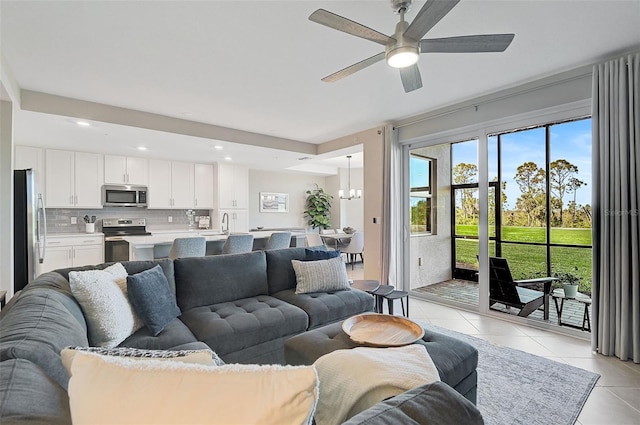 living room with light tile patterned floors, ceiling fan with notable chandelier, and recessed lighting