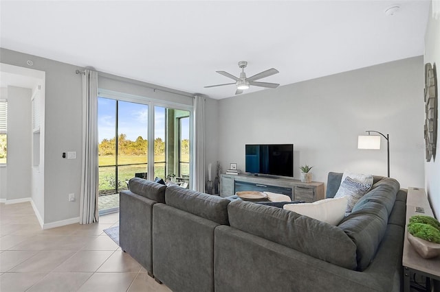 living area with light tile patterned flooring, ceiling fan, and baseboards