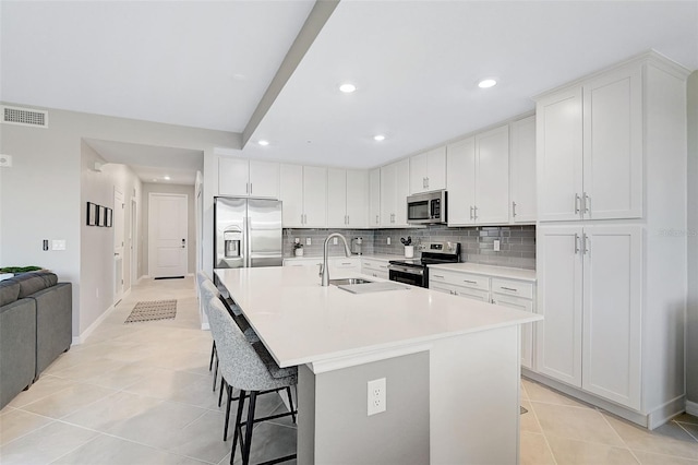 kitchen with a center island with sink, visible vents, white cabinets, appliances with stainless steel finishes, and a sink