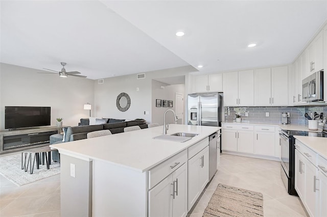 kitchen featuring stainless steel appliances, light countertops, a center island with sink, and white cabinets