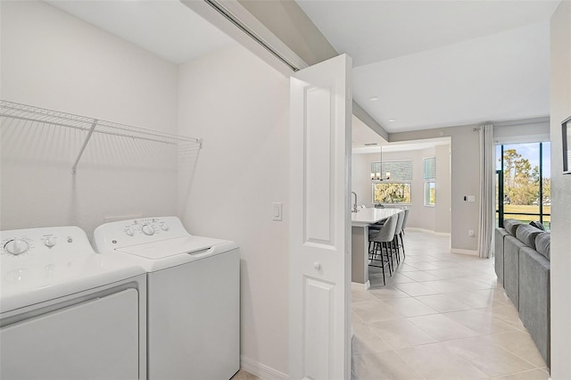 washroom featuring light tile patterned flooring, a notable chandelier, laundry area, baseboards, and washer and clothes dryer