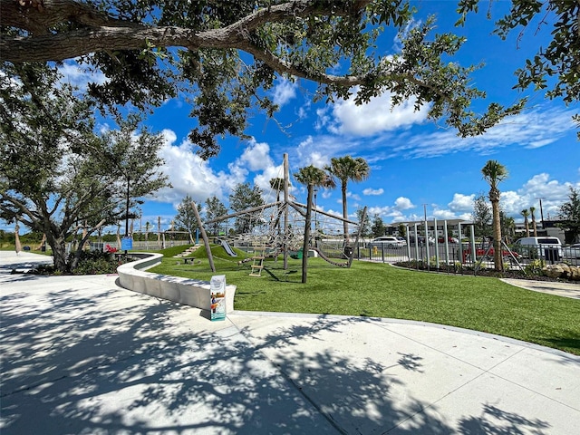 view of home's community with playground community, a lawn, and fence