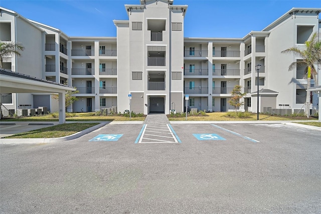 view of building exterior with uncovered parking and cooling unit