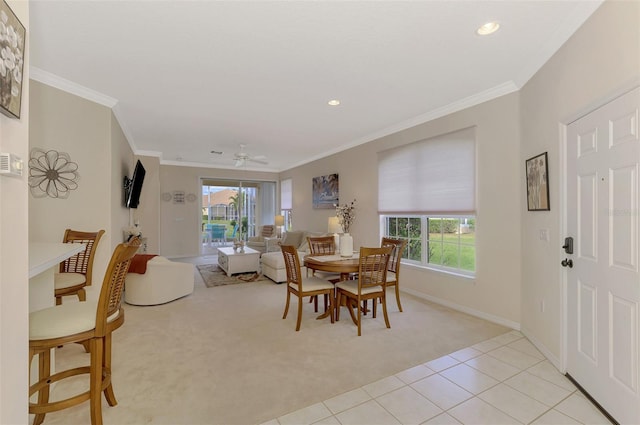 carpeted dining room featuring ceiling fan and crown molding