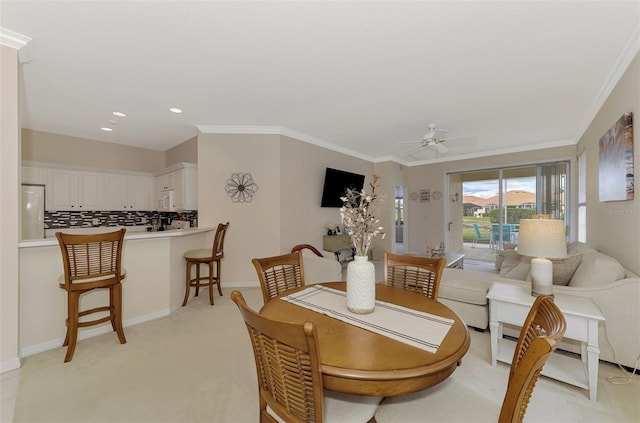 dining room featuring ceiling fan, light colored carpet, and ornamental molding