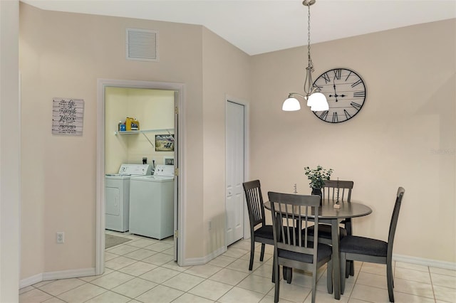 tiled dining room featuring separate washer and dryer and a notable chandelier