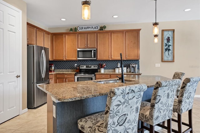 kitchen featuring pendant lighting, a kitchen breakfast bar, light stone countertops, light tile patterned floors, and stainless steel appliances