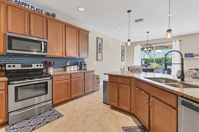 kitchen with light stone countertops, sink, stainless steel appliances, tasteful backsplash, and pendant lighting