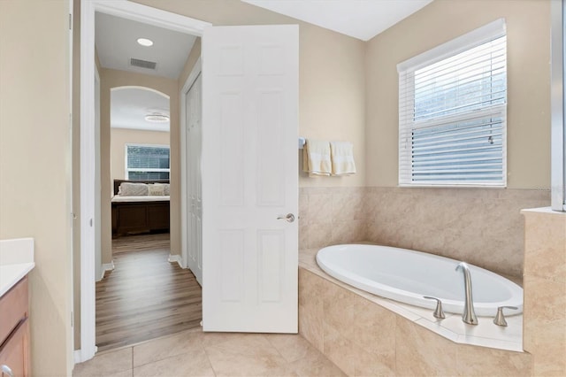 bathroom featuring hardwood / wood-style floors, vanity, and tiled tub