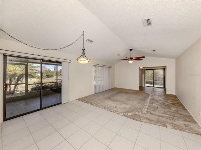 tiled spare room with a textured ceiling, vaulted ceiling, a wealth of natural light, and ceiling fan