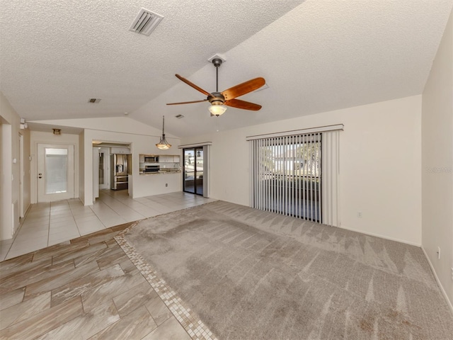 unfurnished living room with ceiling fan, lofted ceiling, a textured ceiling, and light tile patterned floors