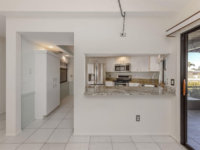 kitchen with white cabinets, sink, light stone countertops, kitchen peninsula, and stainless steel appliances