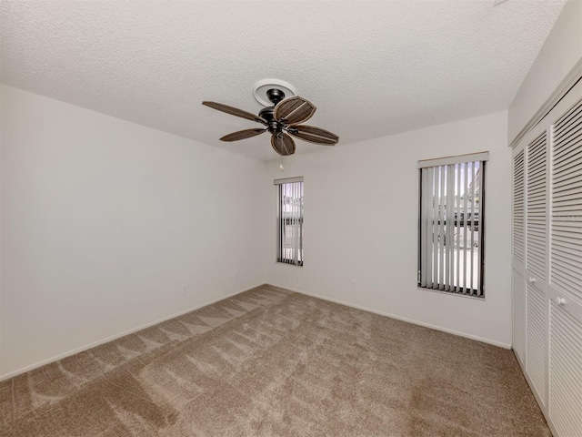 unfurnished room featuring carpet flooring, a textured ceiling, and ceiling fan