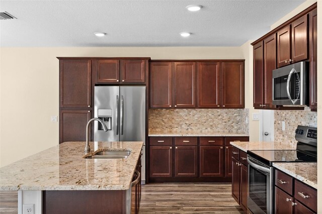 kitchen featuring hardwood / wood-style floors, stainless steel appliances, light stone counters, and sink