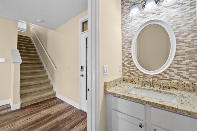 bathroom with tasteful backsplash, vanity, and hardwood / wood-style flooring