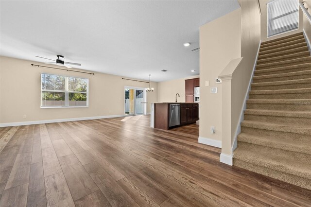 unfurnished living room with ceiling fan with notable chandelier, dark wood-type flooring, and sink